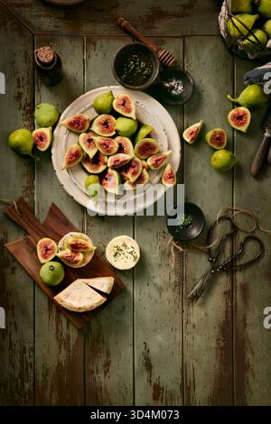 flay lay of ripe figs in plate and in a basket ready to eat with goat cheese and thyme honey, Stock Photo