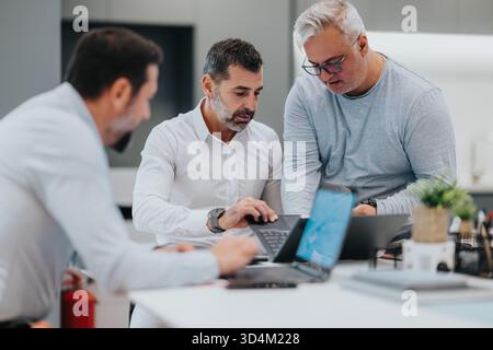 Team of professionals collaborating around laptops in a modern office for business meeting and brainstorming Stock Photo