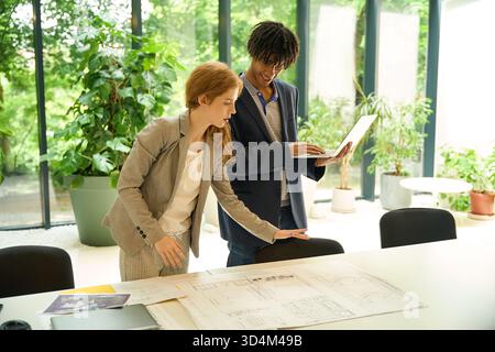 Man and woman discussing over architectural plans Stock Photo