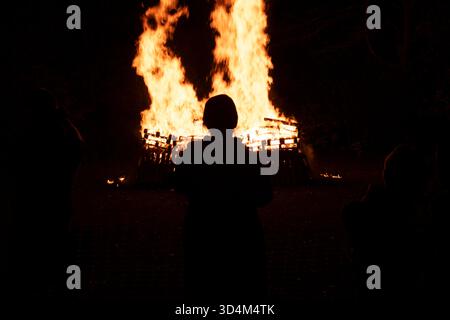 People silhouetted on the Bonfire and Fireworks Night celebrating the failed Gunpowder Plot of 1605, at a communal park in South Wimbledon, London, UK Stock Photo