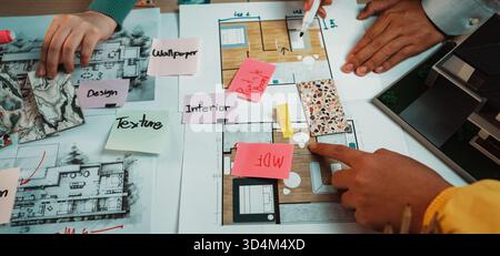A vibrant workspace showcasing a collaborative approach to interior design. Hands actively engage with layouts, color swatches, and design notes for Stock Photo