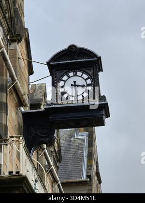 A vintage clock mounted on the side of a stone building, Glasgow, Scotland Stock Photo