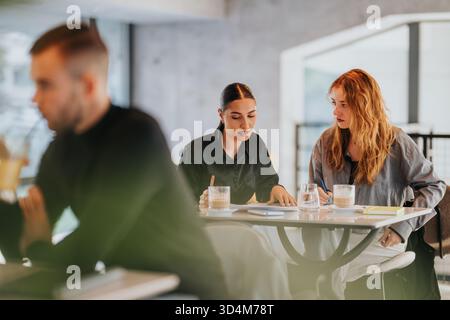 Two colleagues collaborate at a modern office cafe table during a focused meeting Stock Photo