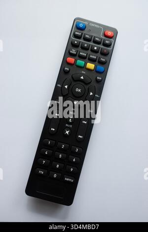 Black TV remote control viewed from above on white background, showing colorful buttons and layout Stock Photo