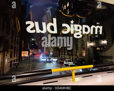 Manchester, UK - September 30, 2025: Night street view in Manchester reflected on Magic bus window with cars and city architecture. Stock Photo