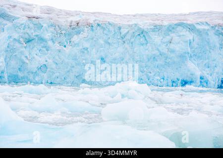 Svalbard cruise - Large wall of ice is covered in snow and ice. The ice is blue and white, and the snow is white. The wall is very tall and very long Stock Photo