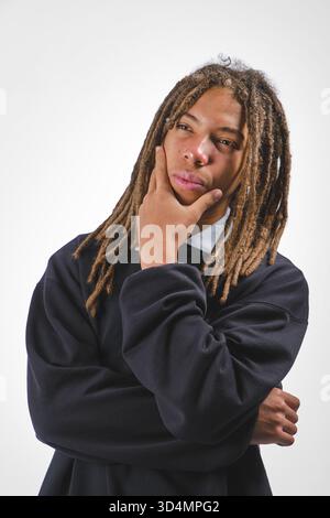 Young man with dreadlocks on a white background, contemplating thoughtfully Stock Photo