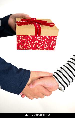 Two people shaking hands with another person holding a christmas gift box. Stock Photo