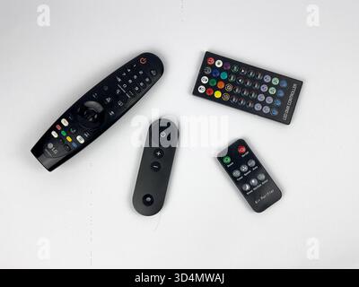 This is a flat lay or top-down view showing four different black remote controls scattered across a plain white background. Stock Photo
