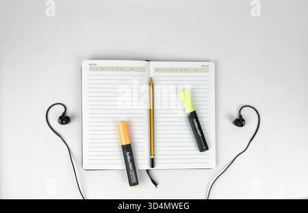 This is a flat lay or top-down view of a clean, minimalist workspace setup. The main subjects are lined notebook or journal and a modern devices Stock Photo