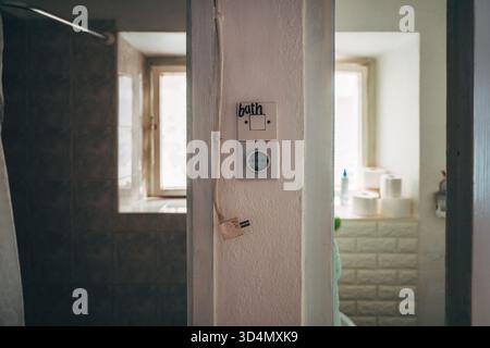 Vintage bathroom light switch with handwritten label "BATH" and old electricity socket, rustic aged bathroom interior detail. Selective focus. Stock Photo