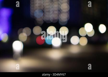 Abstract, blurred background of colorful city lights at night, creating circular bokeh effects. Stock Photo