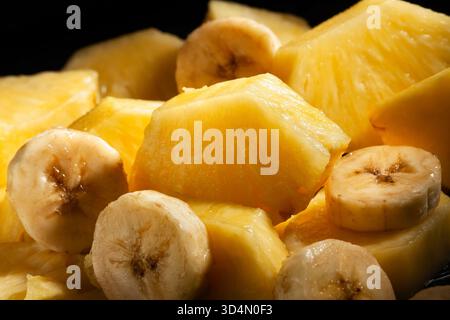 sliced pineapple banana mix on black background Stock Photo