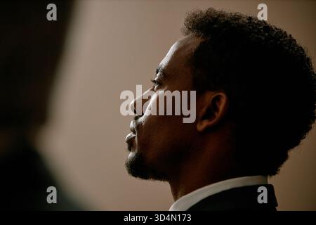 Young Adult Black Man Sitting in Profile during Serious Business Meeting Stock Photo