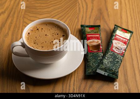 Lviv, Ukraine - November 11, 2025: Overhead View of Hot Cappuccino Cup and Jacobs Instant Sachets Stock Photo