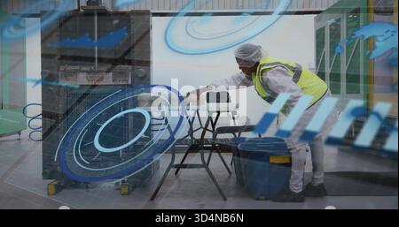 Leaning worker in coveralls hairnet neon vest placing container on sawhorse in plant, copy space Stock Photo