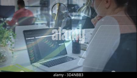 Working woman in dark top focusing on laptop with code dashboard at open-plan office, copy space Stock Photo
