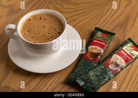 Lviv, Ukraine - November 11, 2025: Overhead View of Hot Cappuccino Cup and Jacobs Instant Sachets Stock Photo