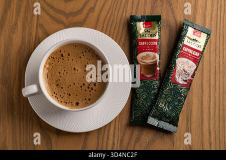 Lviv, Ukraine - November 11, 2025: Overhead View of Hot Cappuccino Cup and Jacobs Instant Sachets Stock Photo
