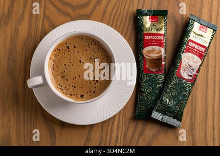 Lviv, Ukraine - November 11, 2025: Overhead View of Hot Cappuccino Cup and Jacobs Instant Sachets Stock Photo