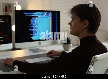 Programmer working on computer with dual monitors at white table in office Stock Photo