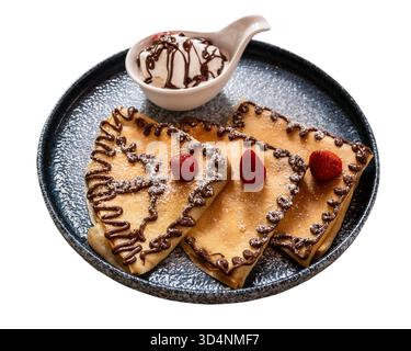 pancakes decorated with chocolate pattern, strawberries and ice cream in separate bowl on ceramic plate cutout on white background Stock Photo