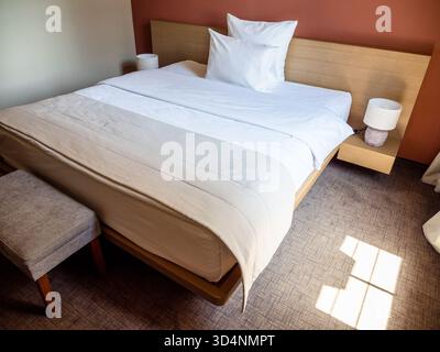 double bed covered with white linens in little apartment room Stock Photo