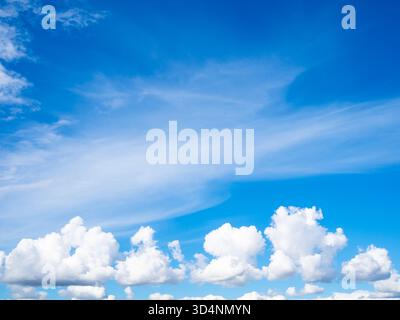 small white cumulus clouds below and white cirrus clouds in blue sky on sunny summer day over St Petersburg city, Russia Stock Photo