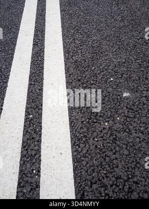 freshly white painted double solid lines on new asphalt road Stock Photo