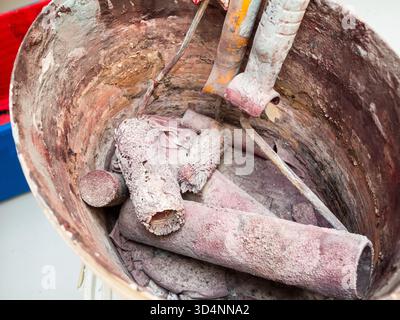several dried used paint rollers in plastic bucket closeup Stock Photo