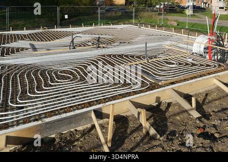 Underfloor heating system installation with white pipes laid in concrete foundation during building construction, efficient energy solution Stock Photo