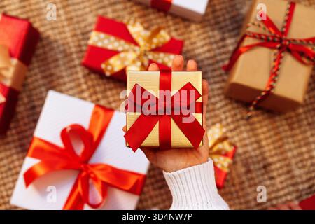 Small gift box wrapped in golden paper with red ribbon in hand Stock Photo