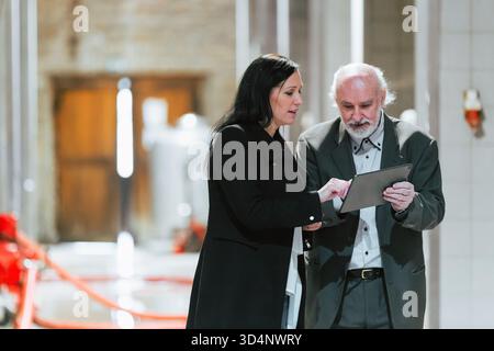 Two individuals collaborate on a project using a tablet in a construction industry site with unfinished surroundings. Stock Photo