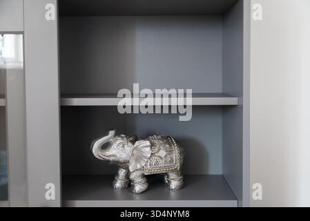 Silver elephant figurine on shelf. Symbolism, protection, and cultural decor in modern home interior. Stock Photo