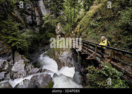 Female hiker on wooden walkway on the Diosaz mountain river in the gorge, Gorges de la Diosaz, Les Houches, Chamonix-Mont-Blanc, Haute-Savoie, France Stock Photo