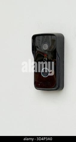 Doorbell camera mounted on white wall, providing home security and surveillance. Mobile photo Stock Photo