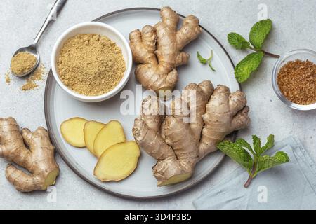 Food, Sliced fresh ginger root, ginger powder and mint leaves on plate, top view Stock Photo
