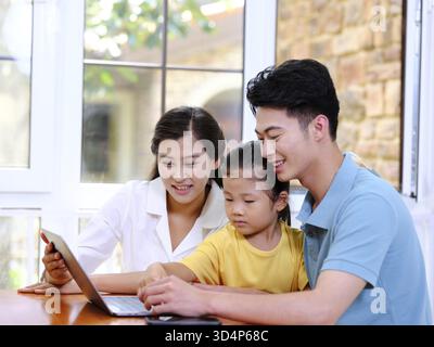 Happy family of three using laptop in the house Stock Photo
