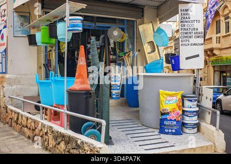 Sliema, Malta - 11.03.2025: Colorful buckets, home goods, tools, paints, and cement displayed outside a small hardware store on a Maltese city street. Stock Photo