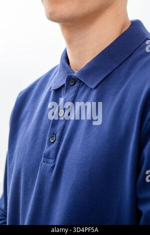 Close-up of navy blue polo shirt collar and buttons on man against white background. Stock Photo