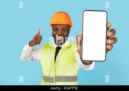 Building Services. Black Construction Worker Demonstrating Blank Smartphone And Showing Thumb Up Stock Photo