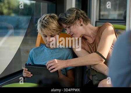 Mother and son using tablet on bus Stock Photo