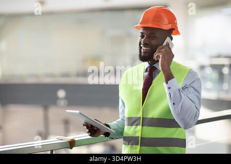 African american architect having phone conversation, using pad Stock Photo