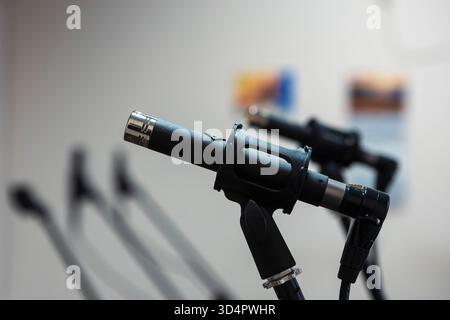 Close-up of microphones in a studio, capturing sound with precision, surrounded by cables and equipment under controlled lighting for recording music Stock Photo