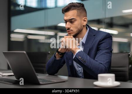 Pensive Young Middle Eastern Businessman Working on Marketing Research in Modern Office Stock Photo
