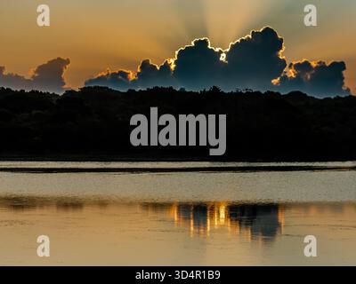 Dawn at one of the entrances to Yala National Park in Sri Lanka. The early morning clouds reflect in a nearby lake. Stock Photo
