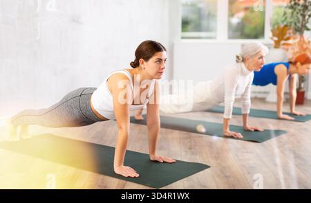 Young focused women doing plank pose in yoga studio Stock Photo
