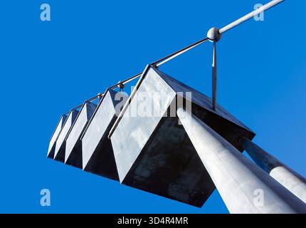 Low-angle view of a modern abstract metal sculpture with geometric shapes suspended on pillars against a clear blue sky palma contemporary art gallery Stock Photo