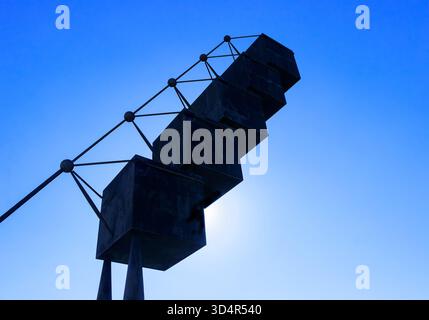 Modern abstract sculpture made of connected geometric black cubes silhouetted against a clear blue sky with sun behind palma contemporary art gallery Stock Photo