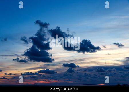 Dramatic evening sky with dark clouds scattered across fading light during sunset over a distant flat horizon can pastilla mallorca spain Stock Photo